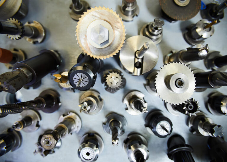 High angle view of metal milling cutters with various bits on steel table